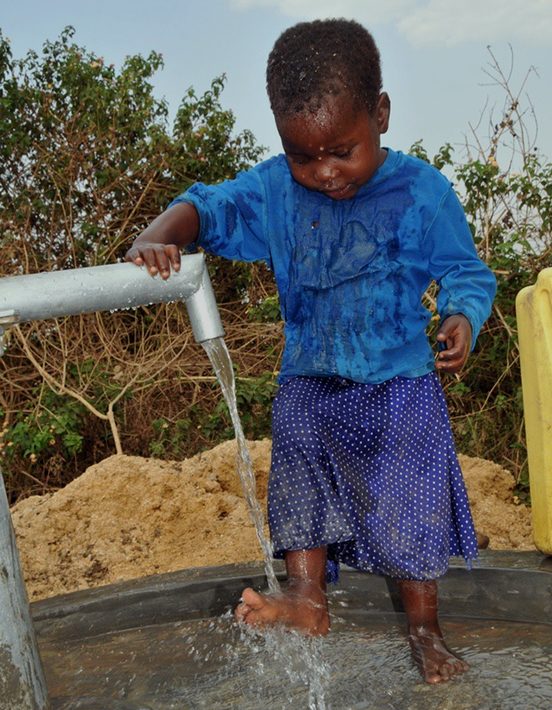 A child collecting clean water from a village pump