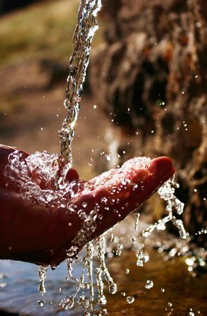 Hands cupped beneath flowing clean water