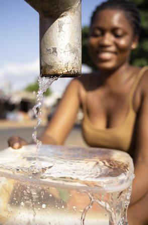 A woman collecting water from a protected spring